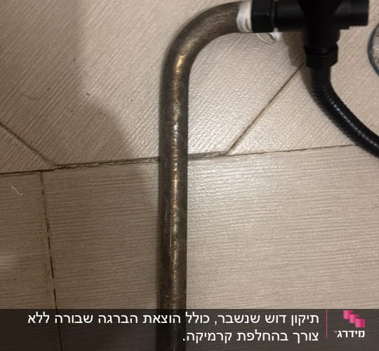 ברז מים שחור מחובר לצינור מתכת מונח על ריצוף